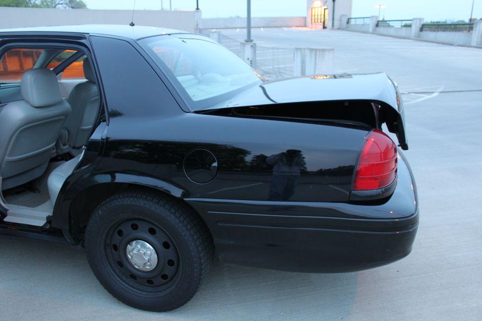 Black sedan rear 3/4 with trunk open, fuel door, red tail lamp and black steel wheel