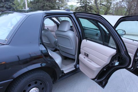 2007 Ford Crown Victoria - Rear door of a black full-size sedan swung wide open, revealing the gray rear bench and the backs of the front seats, plus the gray inner d…