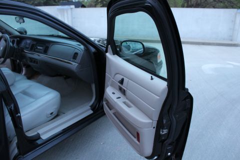 2007 Ford Crown Victoria - Open passenger door of a black full-size sedan on a parking deck, showing the light gray door trim panel with power seat and window switche…
