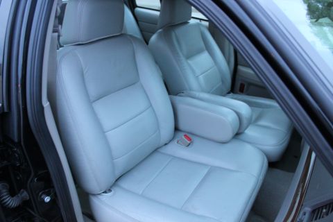 2007 Ford Crown Victoria - Interior view of light gray leather front seats and armrest in a vehicle.