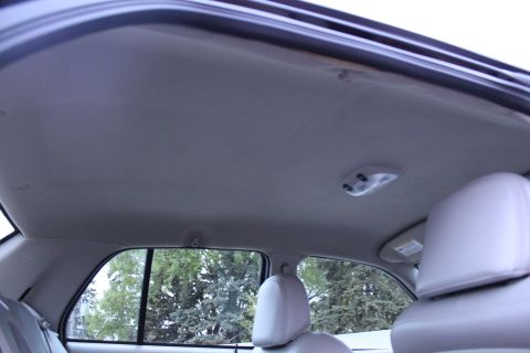 2007 Ford Crown Victoria - Upward view of the light gray cloth headliner in a sedan's rear cabin, with the rear courtesy/map lamp assembly, grab-handle mounting point…