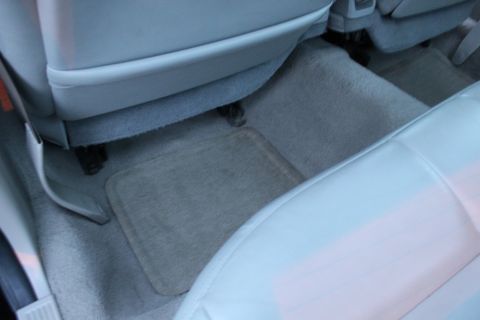 2007 Ford Crown Victoria - Interior shot of a sedan's rear passenger footwell, showing gray carpet with a rectangular carpeted floor mat, the back of the front seat a…