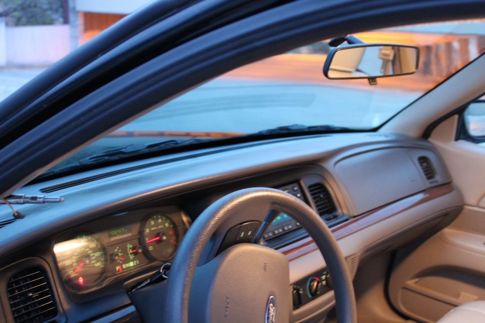 Tan Ford sedan interior with lit green gauges, woodgrain dash trim and gray steering wheel