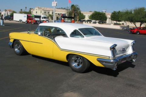 1991 Ford Crown Victoria - A two-tone yellow and white classic car is parked in a lot, with other vehicles and buildings in the background.