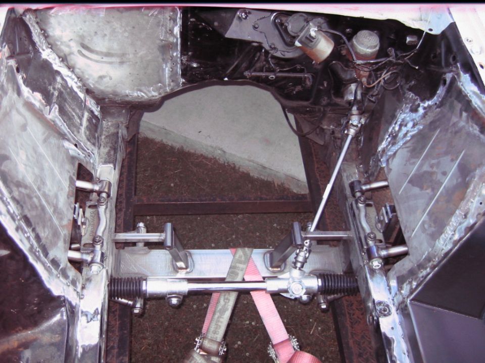 Car chassis showing steering rack and suspension components, appears to be under construction