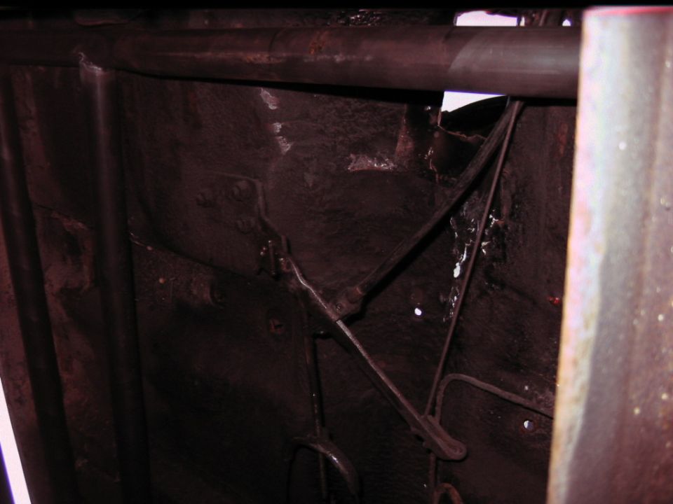 Underside view of vehicle chassis with rust and structural components