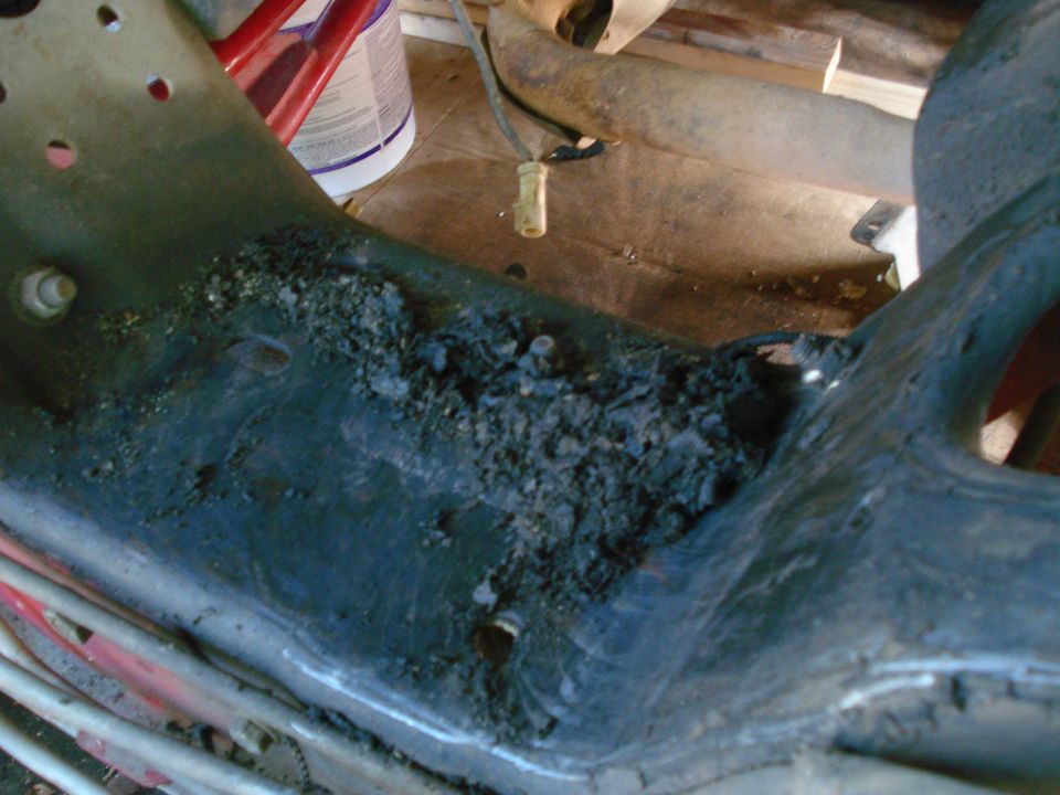 Close-up of a heavily rusted and debris-covered metal frame component, possibly from a vehicle