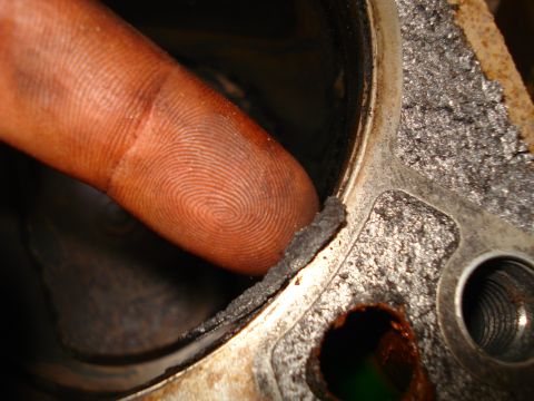 1993 Ford Bronco - A finger indicates a damaged gasket on an engine component, likely from a Ford Bronco rebuild.