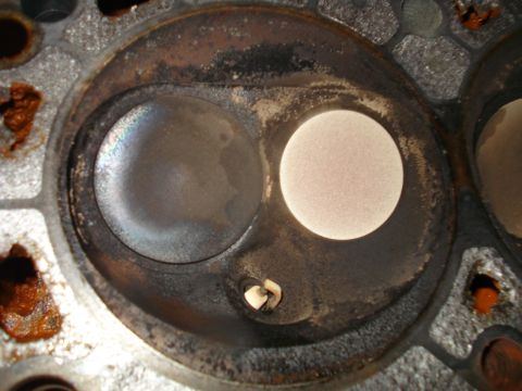 1993 Ford Bronco - Close-up of a cylinder head's combustion chamber showing valve seats and carbon buildup.