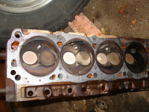 1993 Ford Bronco - A disassembled engine cylinder head with visible valves and signs of wear and tear.