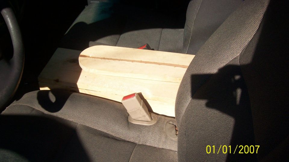 Car interior with wooden object on passenger seat, seatbelt buckle visible