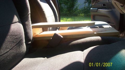 2004 Ford Crown Victoria - A wooden structure is installed between the car seats, with a seatbelt buckle visible.