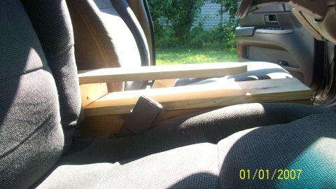 2004 Ford Crown Victoria - The interior of a 2004 Ford Crown Victoria is visible, with a custom wooden structure installed between the seats.