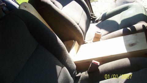 2004 Ford Crown Victoria - Car interior with seats and a wooden support structure between them.
