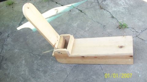 2004 Ford Crown Victoria - A wooden device with a hinged lever sits on a cracked concrete surface.
