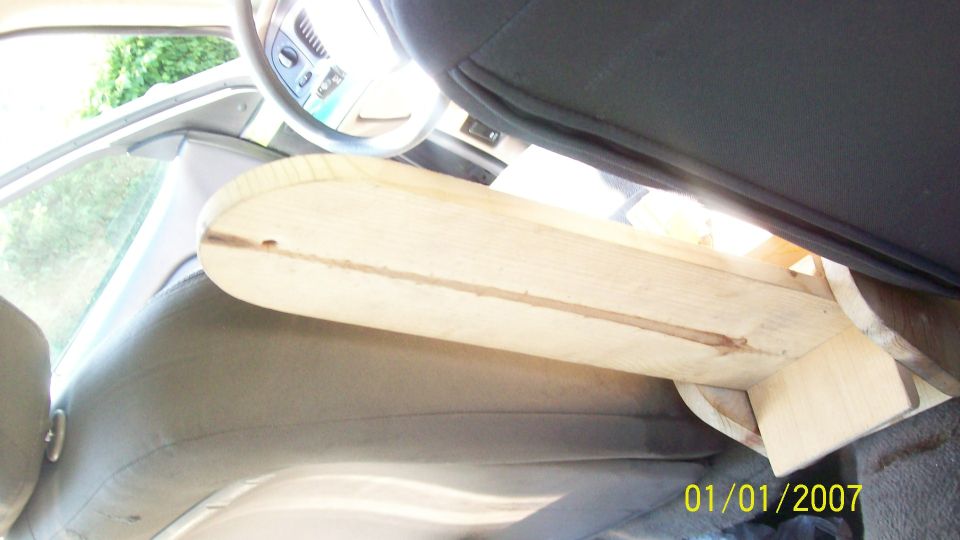 Interior shot of a car with a custom wooden structure installed between the seats, obscuring the view of the dashboard and steering wheel