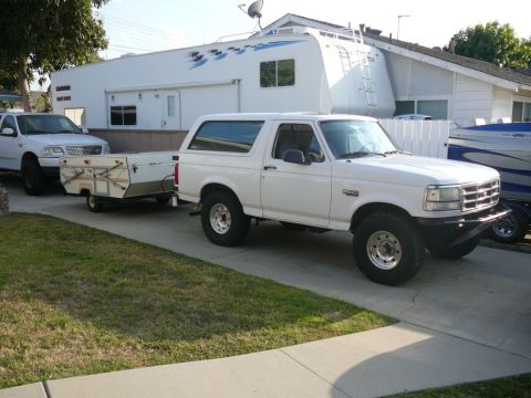 1988 Ford Bronco - This white Ford Bronco, likely a 1992 model, is seen from a 3/4 front angle towing a pop-up camper.