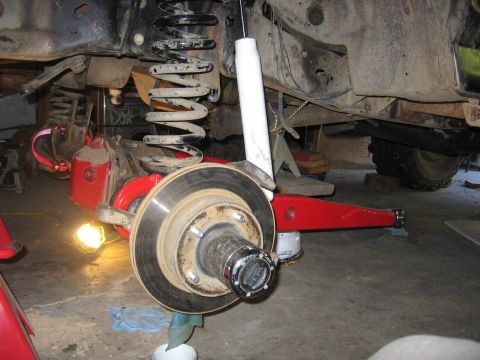 1989 Ford Bronco - Front suspension components of a Ford Bronco undergoing maintenance, showing the brake assembly and shock.