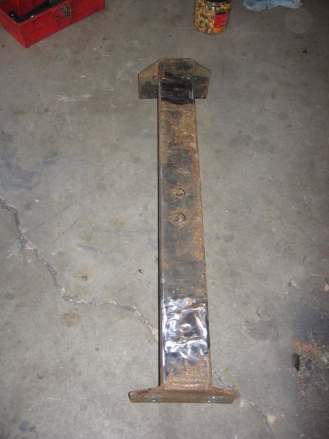 1989 Ford Bronco - This appears to be a single, rusty metal component, likely a part for a vehicle, resting on a garage floor.