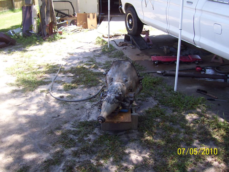 Transmission on wooden blocks, white truck raised on ramps in background
