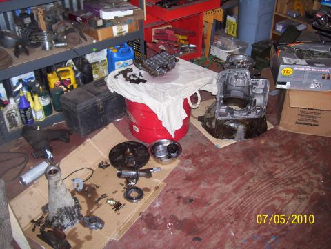 1978 Ford Bronco - Various vehicle transmission components are laid out in a workshop, suggesting a repair or rebuild in progress.