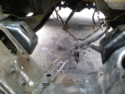 1990 Ford Bronco - Underside view of vehicle frame and suspension components, showing brake lines and mounting brackets.
