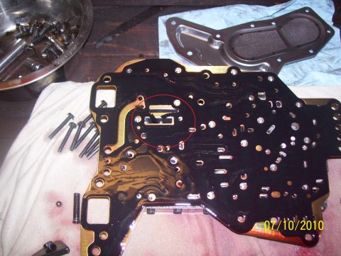 1978 Ford Bronco - Close-up of an automatic transmission valve body with a red circle marking a specific part.