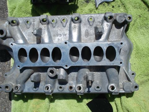 1993 Ford Bronco - Close-up of an aluminum intake manifold, showing ports and casting marks, on a green towel.