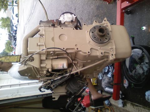1990 Ford Bronco - A tan diesel engine, likely undergoing a swap, is mounted on an engine stand with various hoses and a fuel filter attached.