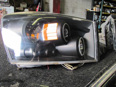 2005 Dodge 3500 - A single vehicle headlight assembly is shown, likely for a truck or SUV, with its turn signal illuminated.