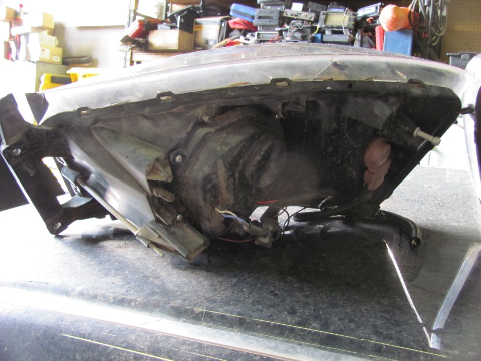 Backside of a vehicle headlight assembly, showing wiring and mounting points