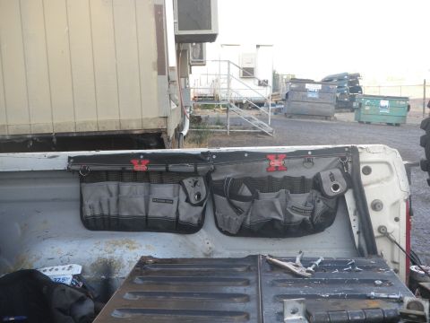 1991 Ford Bronco - Tool organizers hang from the sides of a pickup truck bed, with a pair of vise grips on the tailgate.