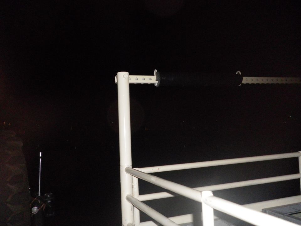 White metal railing with black bar against a dark background
