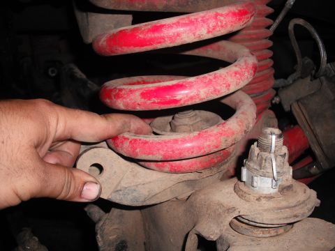 1991 Ford Bronco - Close-up of vehicle suspension components, including a red coil spring and linkage.