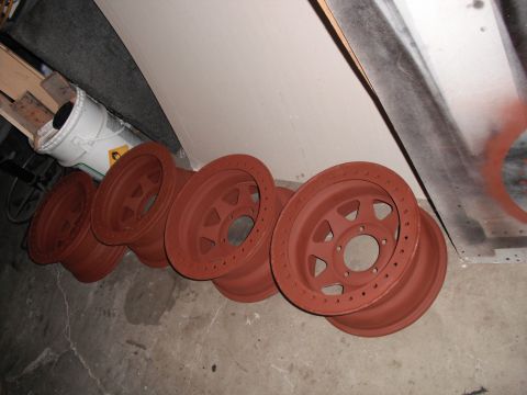 1991 Ford Bronco - Five wheels, likely for an off-road vehicle, are shown coated in red primer.