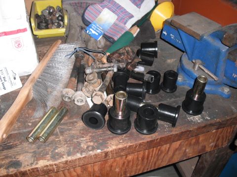 1991 Ford Bronco - Various vehicle suspension parts and tools are laid out on a wooden workbench.