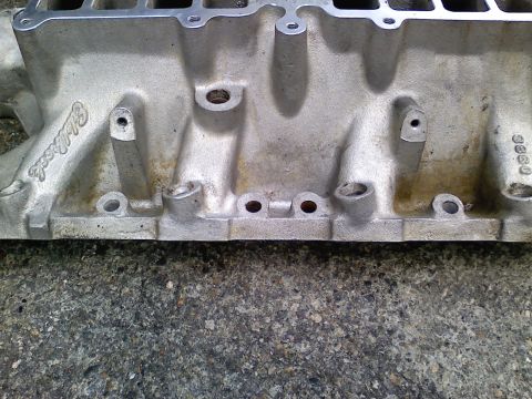 1990 Ford Bronco - Close-up of an aluminum intake manifold with visible Edelbrock branding and casting marks.