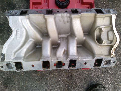 1990 Ford Bronco - An aluminum intake manifold is shown from above, with visible ports and casting marks.