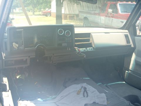 1994 GMC Suburban - The dashboard of a truck is partially disassembled, with tools laid out on a cloth on the floor.