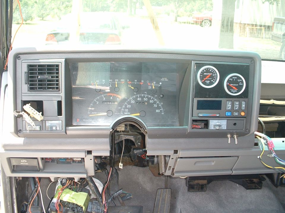 Dashboard of a 1995 GMC Suburban with exposed wiring and aftermarket gauges