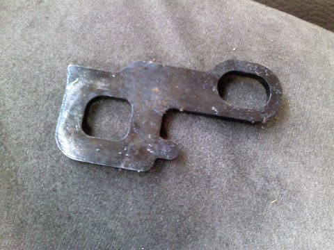 1990 Ford Bronco - A close-up view of a worn metal bracket with multiple holes and signs of rust.