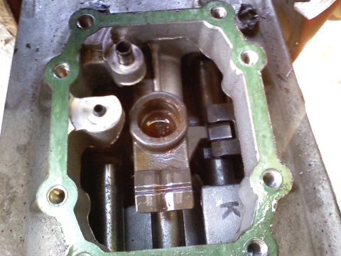 1990 Ford Bronco - Close-up view of an internal engine component, showing a green gasket and mechanical parts. A letter 'K' is visible on a metal piece.