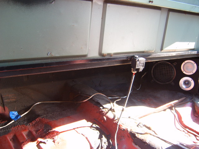 Interior view of a vehicle showing speakers, wiring, and red floor material