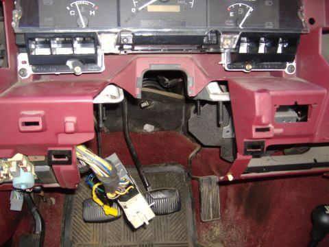 1995 Ford F-150 - Exposed wiring and components under the dashboard of a vehicle, with pedals visible on the floor.