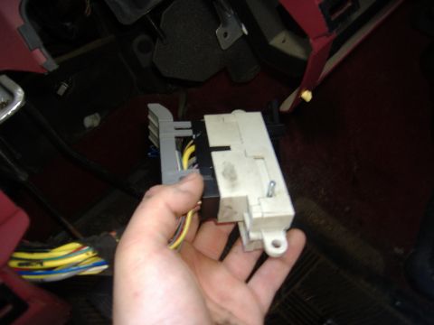 1995 Ford F-150 - A hand holds a steering column electrical connector with visible wiring, suggesting an interior repair or diagnostic.