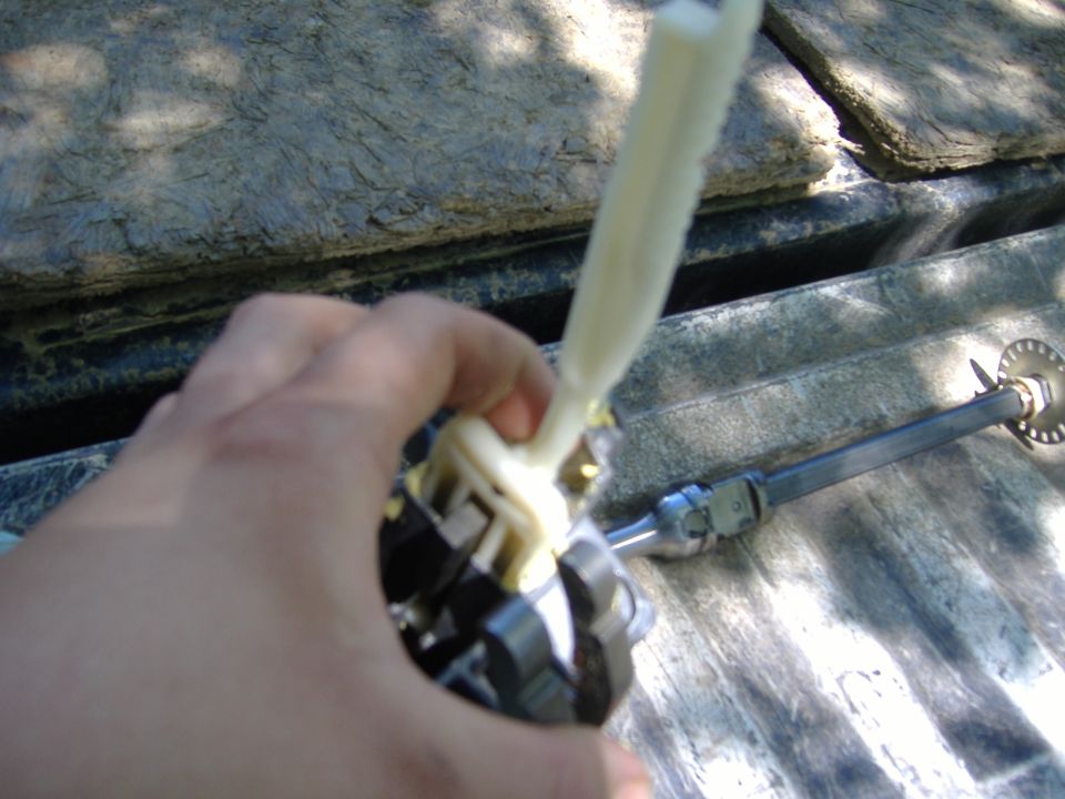 Hand holding a white plastic and metal steering column component