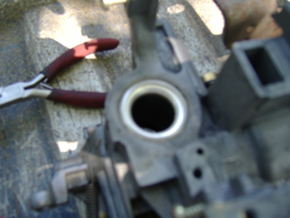 pliers next to a metal part with a circular opening, possibly from a steering column
