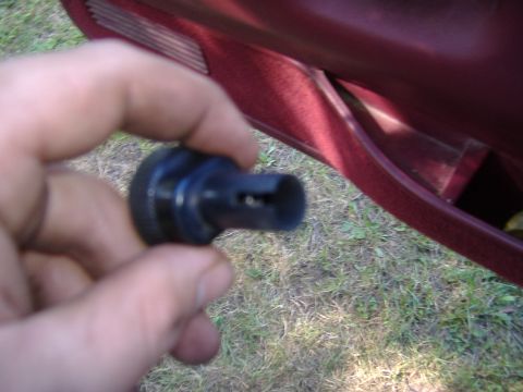 1995 Ford F-150 - Close-up of a hand holding a black plastic part, with a red car door interior visible.