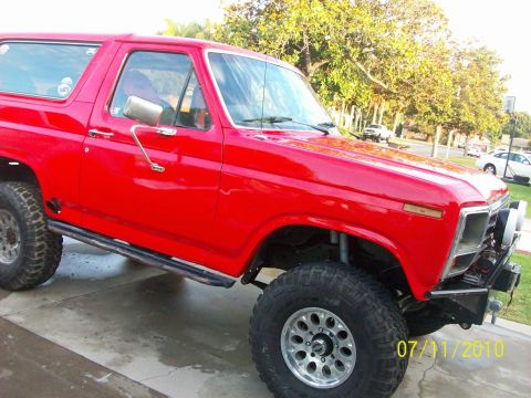 1985 Ford Bronco - This red Ford Bronco has been modified for off-road use with large tires and a custom bumper.
