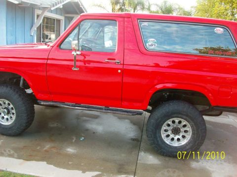 1985 Ford Bronco - Side view of a red SUV, likely from the 1980s, off-road tires and running boards. A date stamp indicates the photo was taken on July 11, 20…
